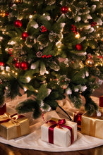 Load image into Gallery viewer, A decorated Christmas tree with red ornaments, warm white string lights, and white snow-dusted branches, with wrapped gift boxes under a white tree skirt on a wooden floor.
